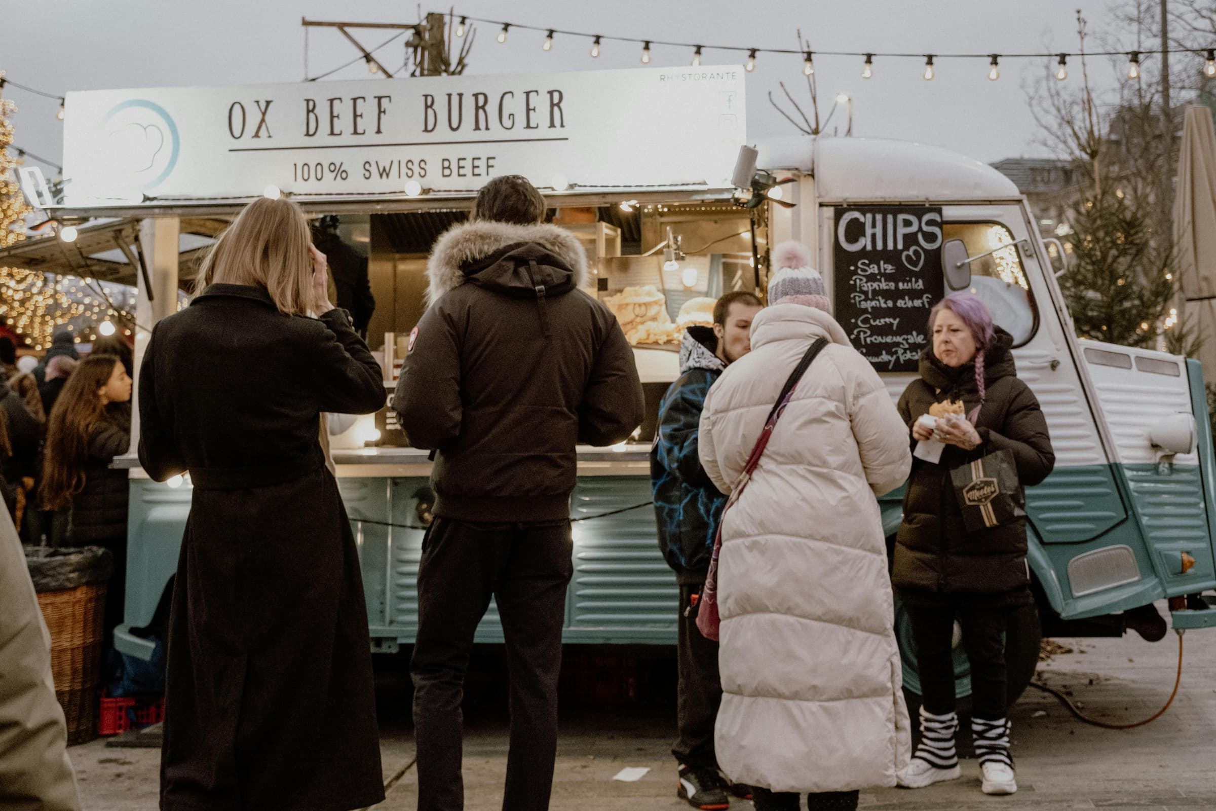 Two food trucks side by side serving customers at an outdoor market